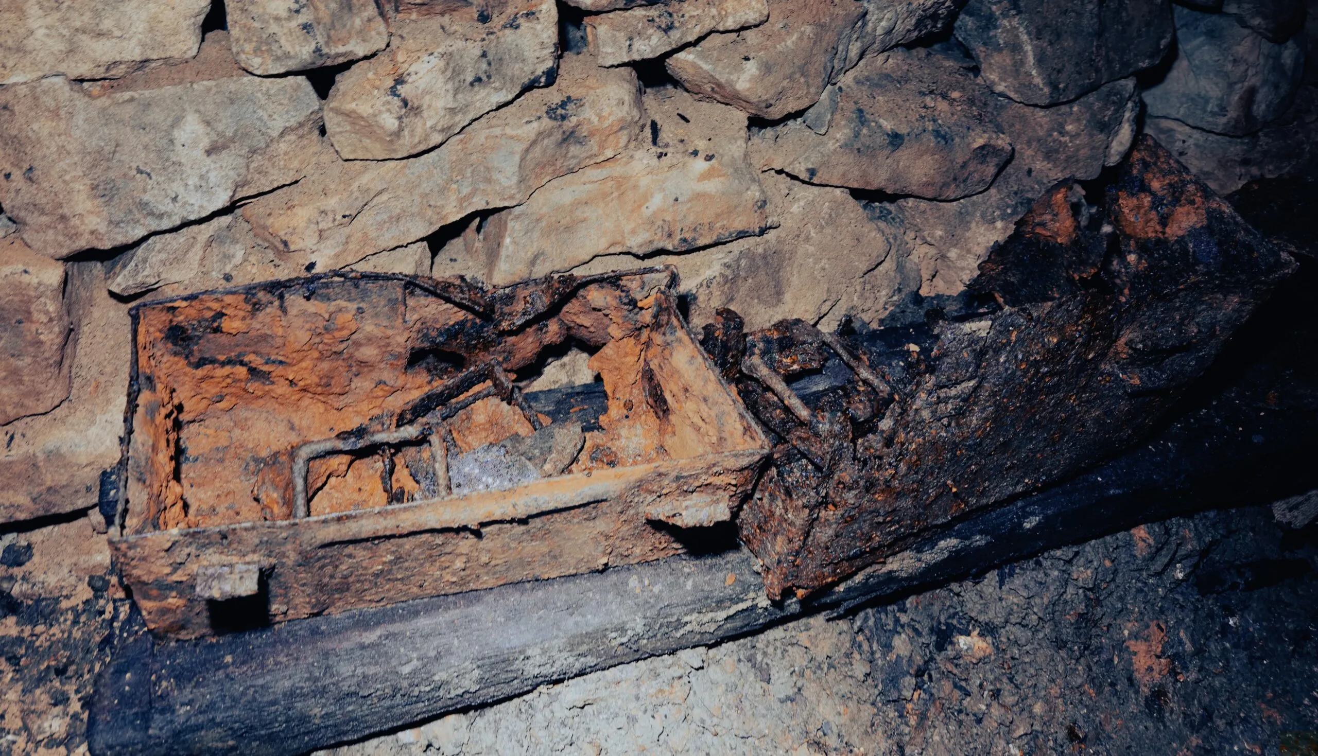 The rusted iron body of a mine tub lying collapsed across the remains of a wooden rail